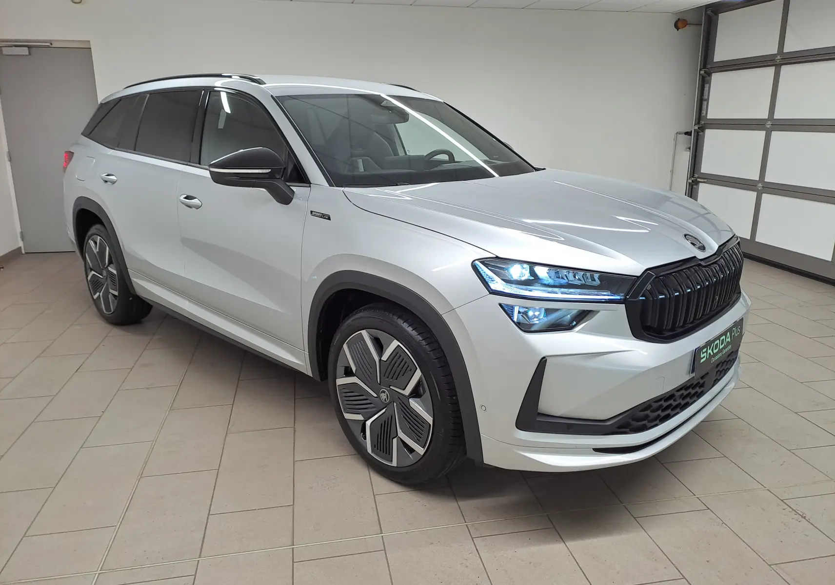 Vue 3/4 avant droite du Skoda Kodiaq gris argent 2025 avec calandre noire et jantes alliage 20 pouces design aérodynamique.