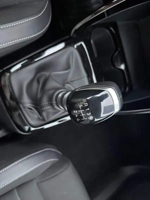 Vue rapprochée du levier de vitesse manuel noir de la Citroën C3 Turbo 100 ch, entouré de sièges gris foncé.