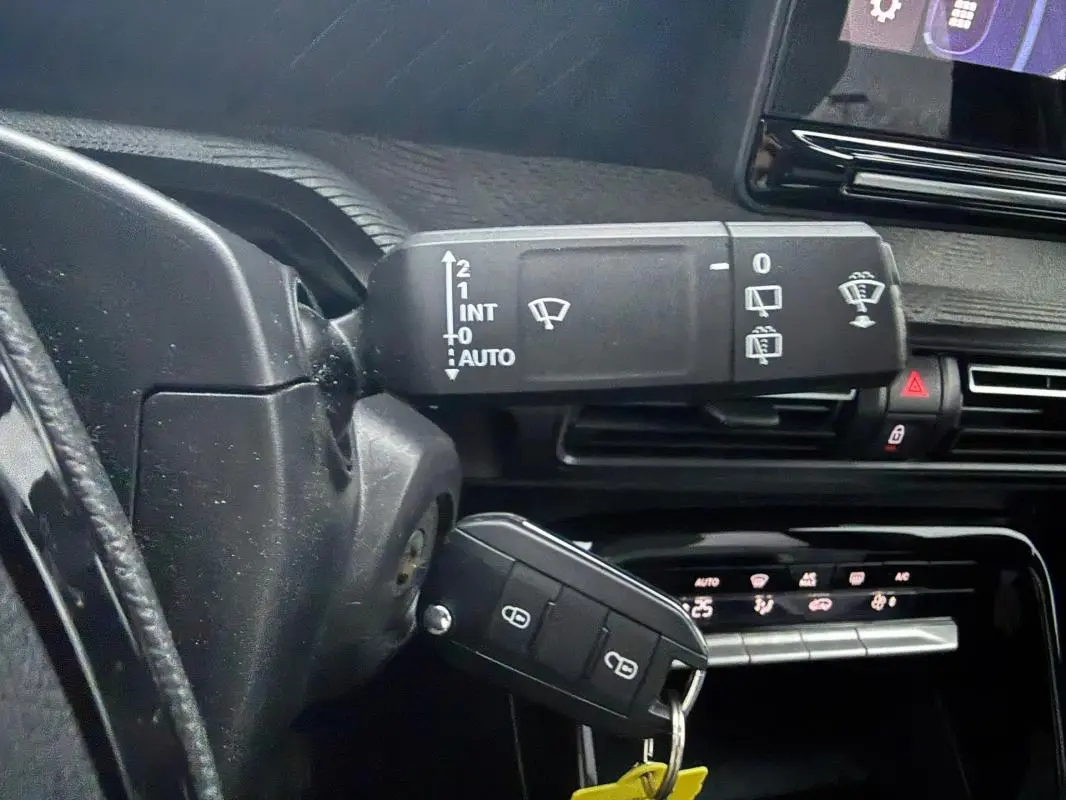 Gros plan sur la commande d’essuie-glace et la clé insérée dans le contacteur d’une Citroën C3 gris, intérieur noir.