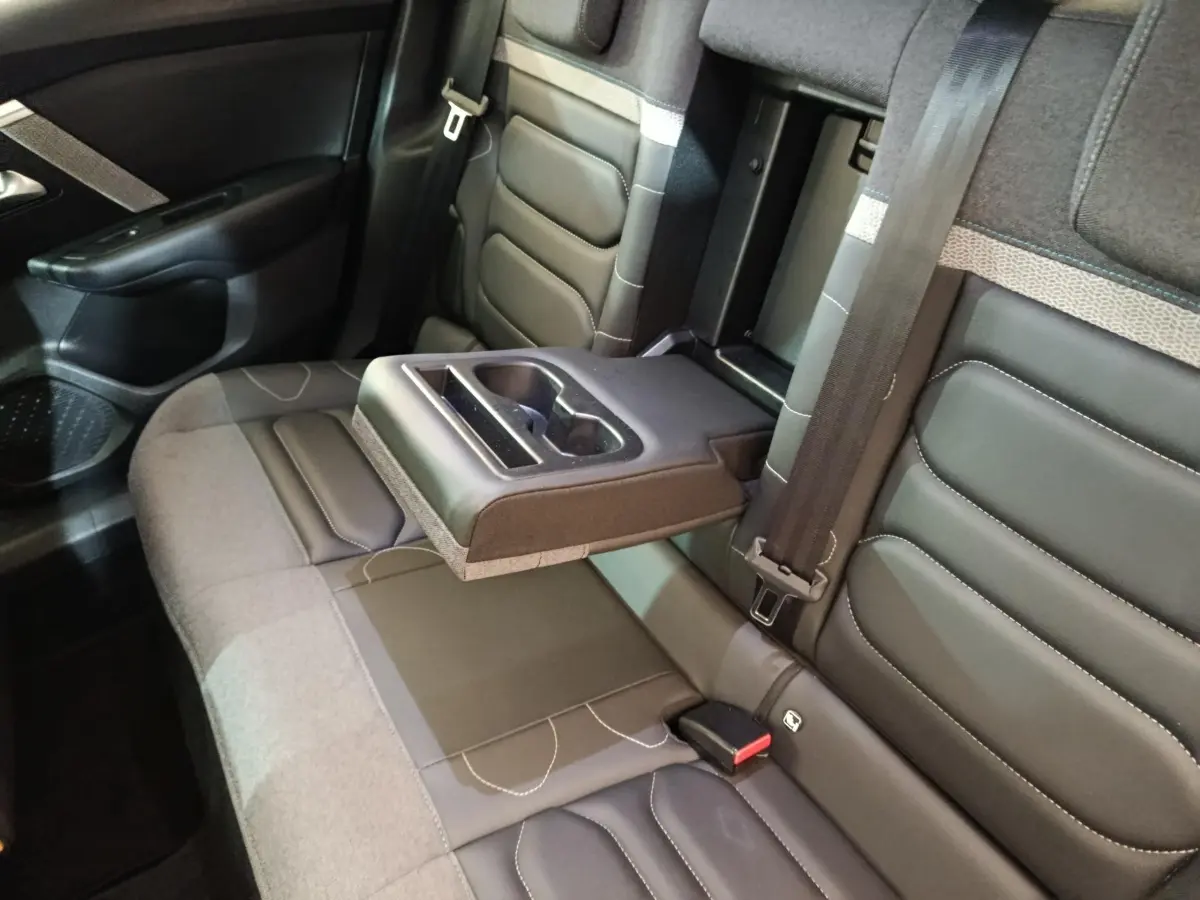 Vue intérieure des sièges arrière gris foncé de la Citroën C4 avec accoudoir central relevé et porte-gobelets intégré.