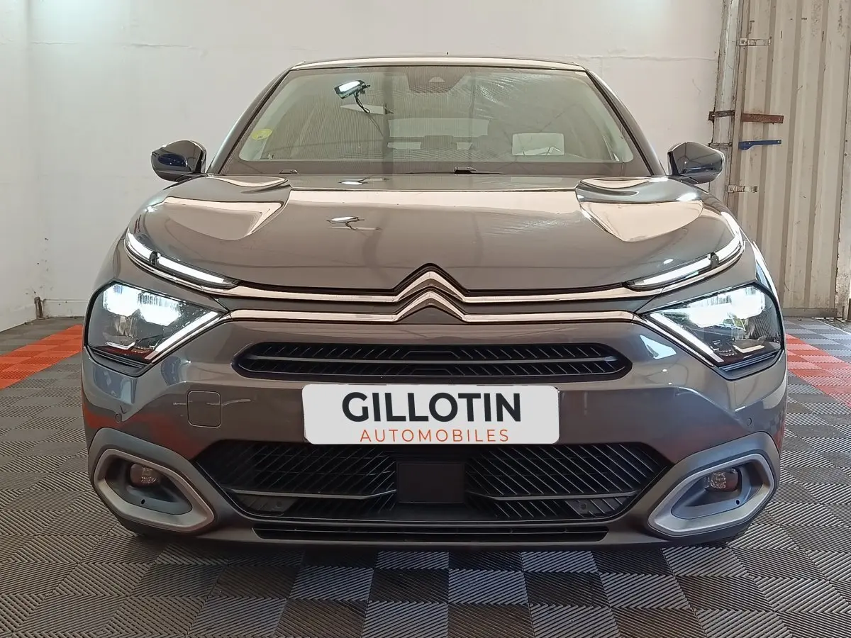 Vue frontale d'une Citroën C4 gris foncé 2022 avec phares LED allumés et calandre distinctive double chevron.