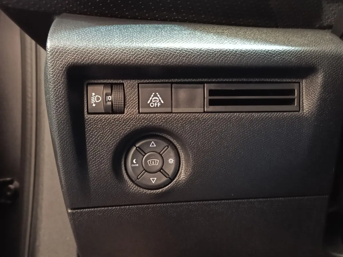 Gros plan sur les commandes de réglage des phares et de l'aide au maintien de voie, tableau de bord noir intérieur Citroën C4.