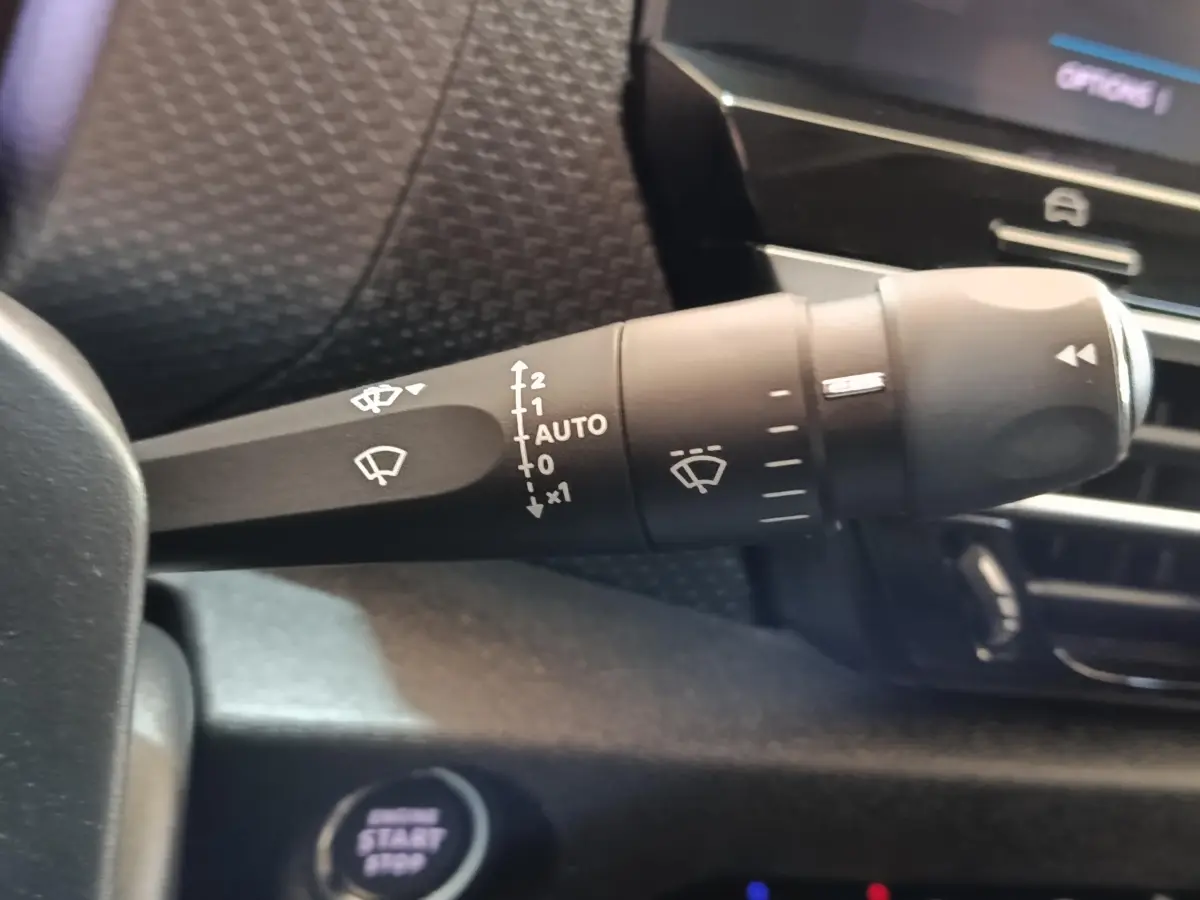 Gros plan sur la commande des essuie-glaces à gauche du volant dans l’habitacle gris foncé de la Citroën C4 2022.