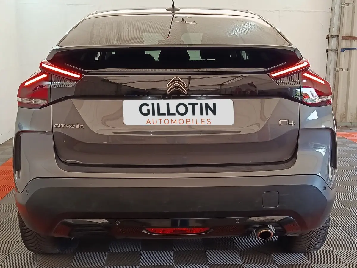 Vue arrière d'une Citroën C4 gris foncé avec feux arrière LED allumés dans un garage.