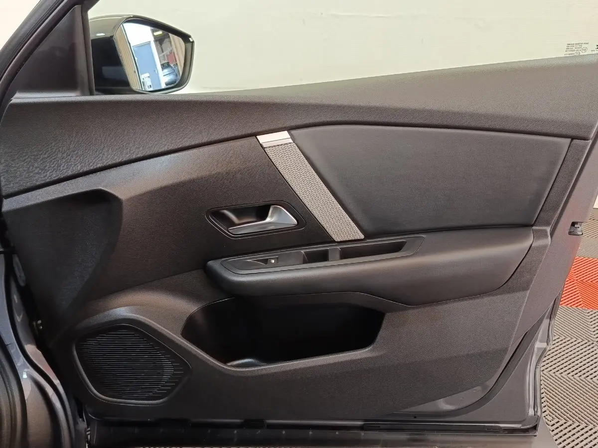 Vue intérieure côté gauche de la porte avant gris foncé de la Citroën C4 2022 avec poignée et haut-parleur intégré.
