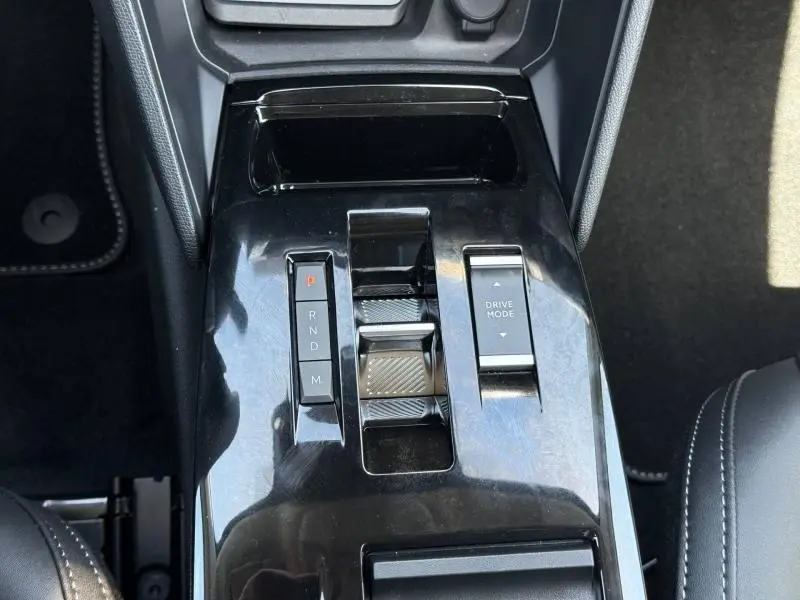 Vue rapprochée de la console centrale noire brillante avec commandes de boîte auto et mode de conduite de la Citroën C4.