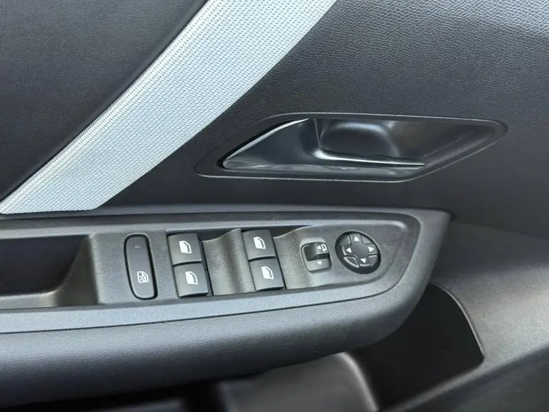 Gros plan sur la commande des vitres et rétroviseurs côté conducteur du Citroën C4 gris Mercury avec insert tissu gris.