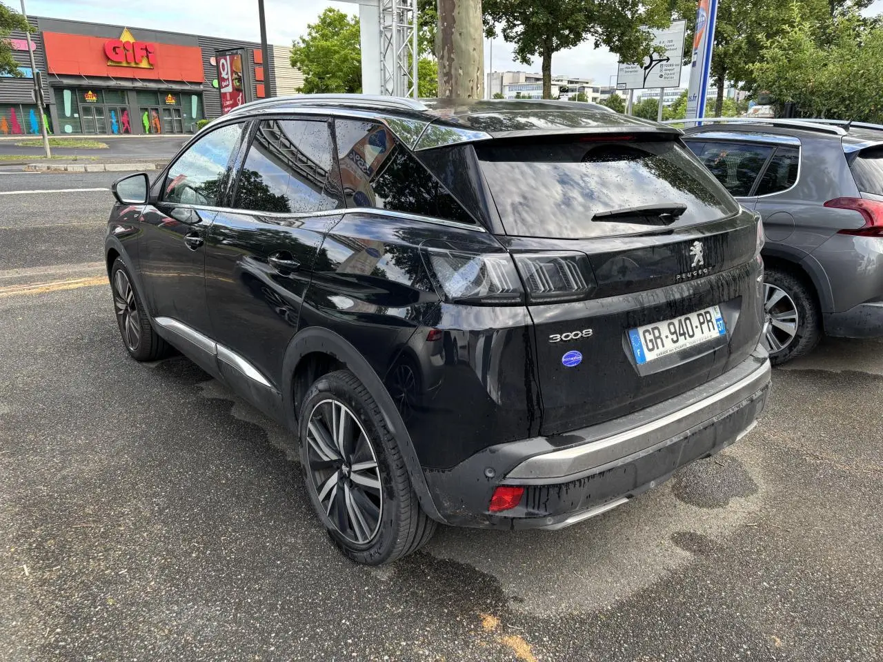 Peugeot 3008 noir métallisé vu en 3/4 arrière droit, avec jantes alliage 19 pouces et vitres surteintées.