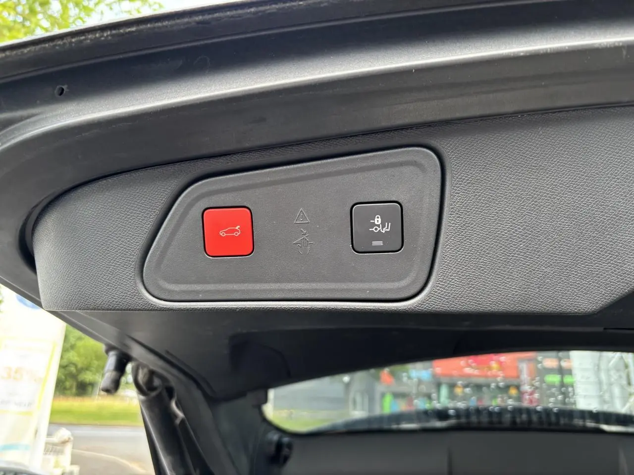 Gros plan sur le panneau de commande du hayon motorisé du Peugeot 3008 noir, avec bouton rouge d'ouverture et bouton de verrouillage.