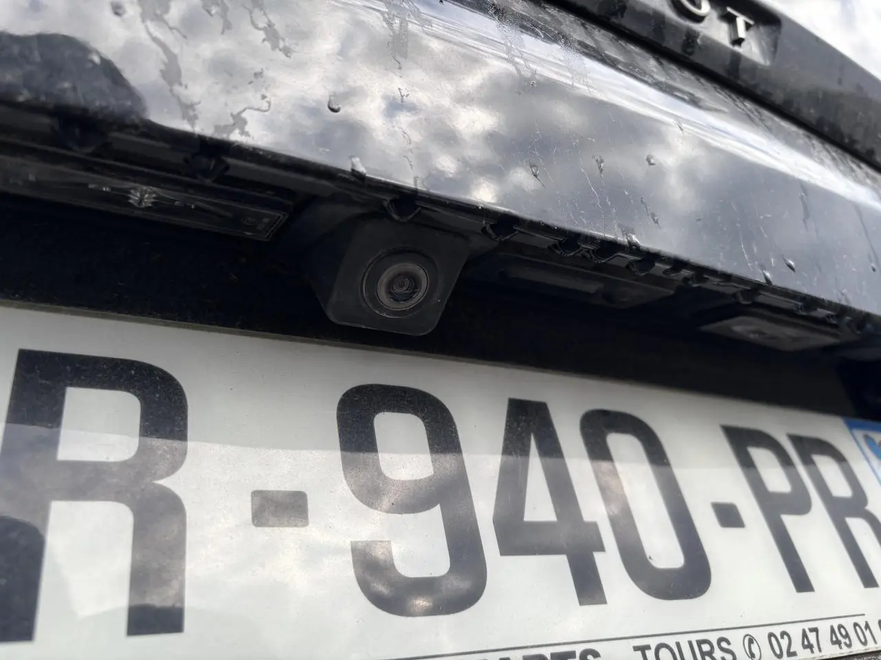 Gros plan sur la caméra de recul et la plaque d’immatriculation d’un Peugeot 3008 noir, arrière du véhicule.