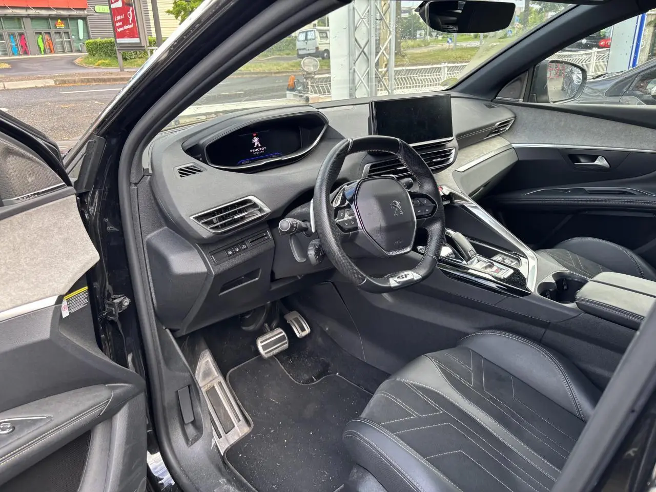 Vue intérieure côté conducteur du Peugeot 3008 noir 2022, mettant en valeur le tableau de bord digital et le volant compact multifonctions.