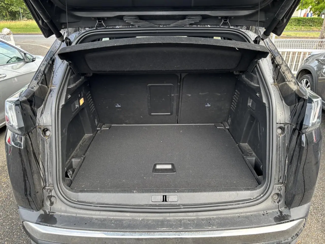 Coffre ouvert d'un Peugeot 3008 noir vu de l'arrière, montrant un espace de chargement spacieux et propre.