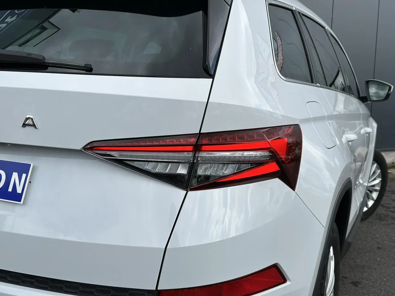 Vue 3/4 arrière droite d'un Skoda Kodiaq blanc glacier avec feux arrière LED et jantes alliage 18 pouces.