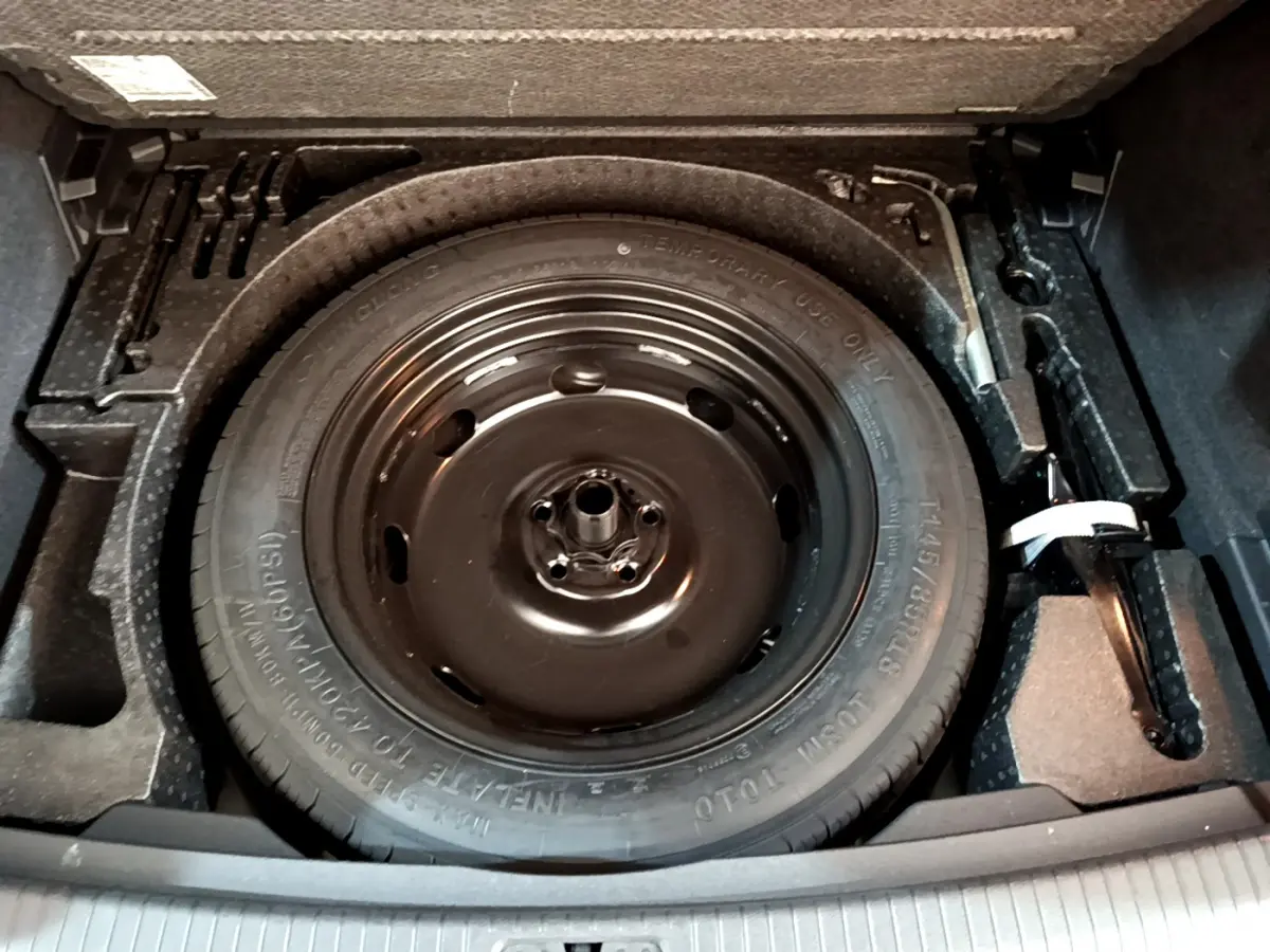 Gros plan sur la roue de secours noire dans le coffre du Volkswagen Tiguan gris clair 2021.