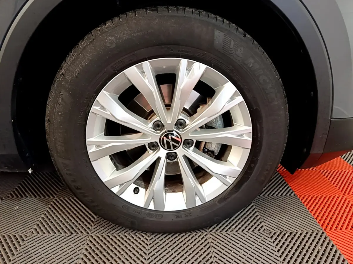 Gros plan sur la roue avant droite du Volkswagen Tiguan gris clair, jante alliage à multiples branches fines.