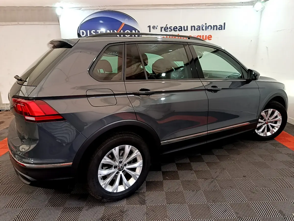 Volkswagen Tiguan gris clair vu de profil droit en intérieur avec jantes alliage et feux arrière LED.