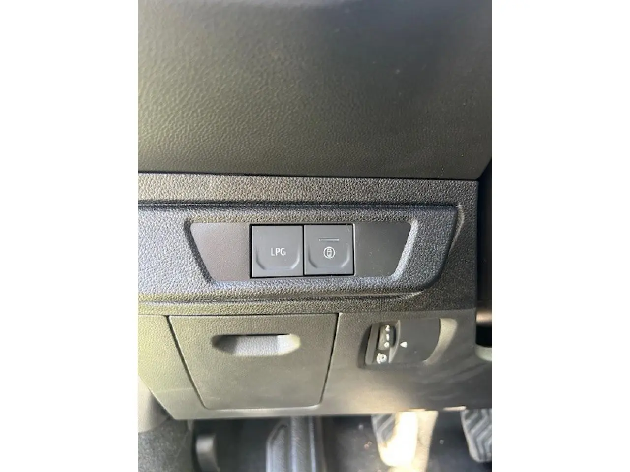Détail intérieur montrant les boutons de commande LPG et verrouillage, sur tableau de bord noir du Dacia Sandero Stepway.