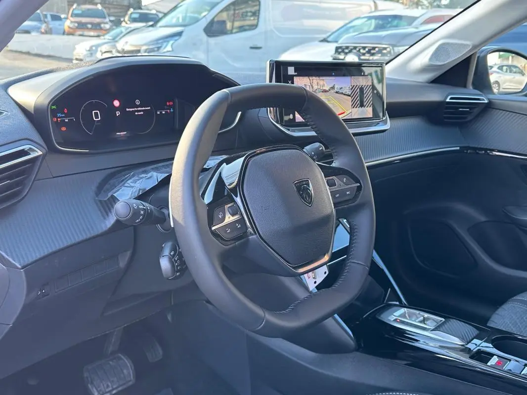 Vue intérieure de la Peugeot 208 Hybrid 110 Allure 2025, montrant le volant compact et l’écran tactile avec caméra de recul.