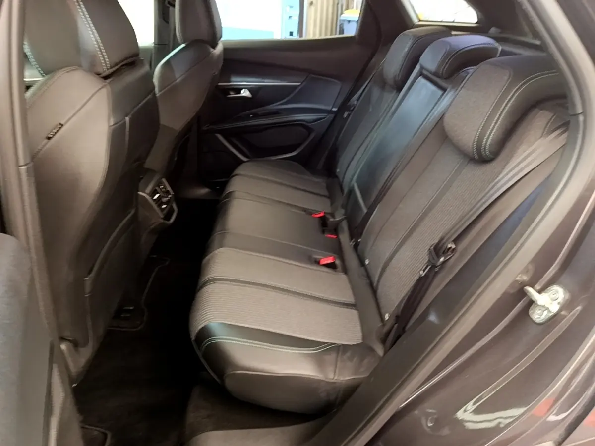 Vue côté droit de la banquette arrière en tissu et cuir noir du Peugeot 3008 gris foncé, avec ceintures et appuie-têtes visibles.