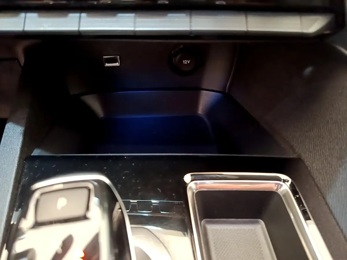 Gros plan sur la console centrale noire brillante du Peugeot 3008 avec levier de vitesses automatique et prise 12V.