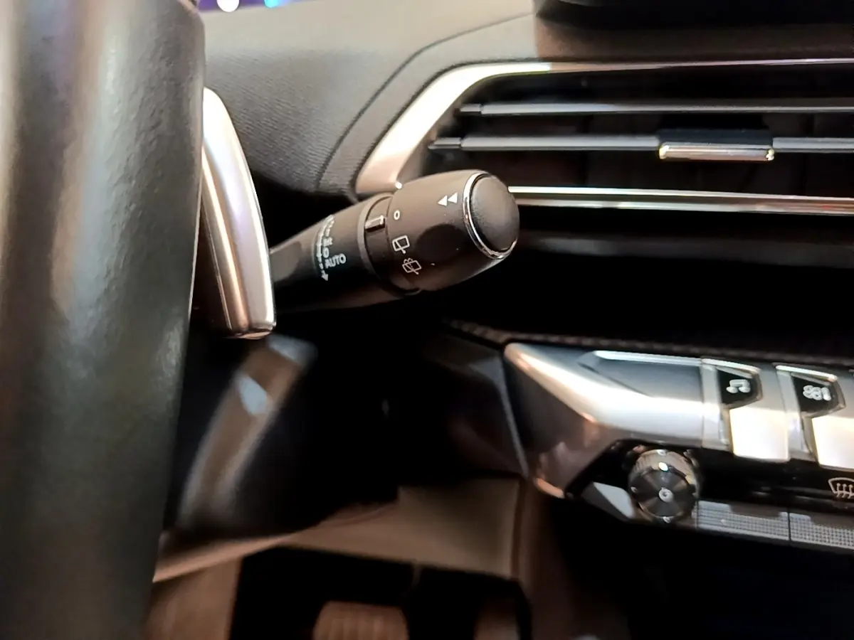 Détail intérieur du volant et commande d’essuie-glace du Peugeot 3008 2022, finition Allure, en gris foncé.