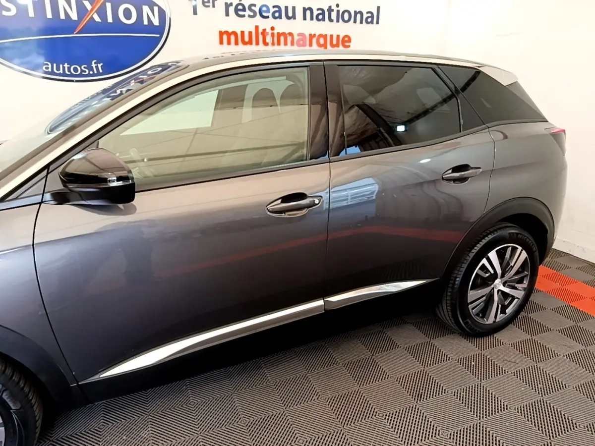 Vue latérale droite d'un Peugeot 3008 gris foncé 2022, avec jantes alliage et vitres teintées, en intérieur showroom.