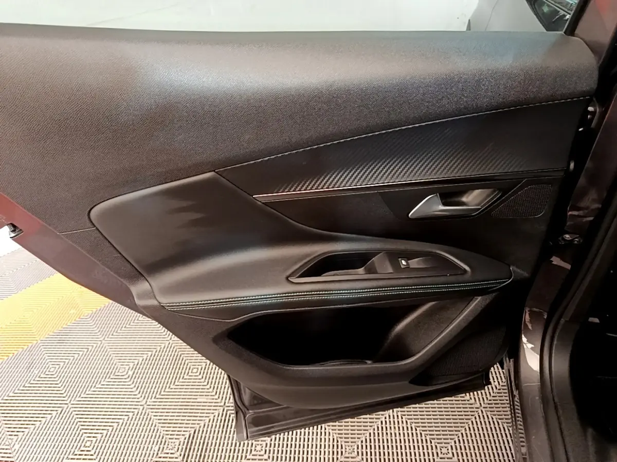 Intérieur de la porte côté gauche du Peugeot 3008 gris foncé, avec garniture noire et insert effet carbone.