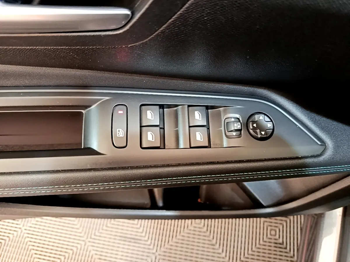 Vue rapprochée du panneau de commandes des vitres et rétroviseurs côté conducteur du Peugeot 3008 gris foncé 2022.
