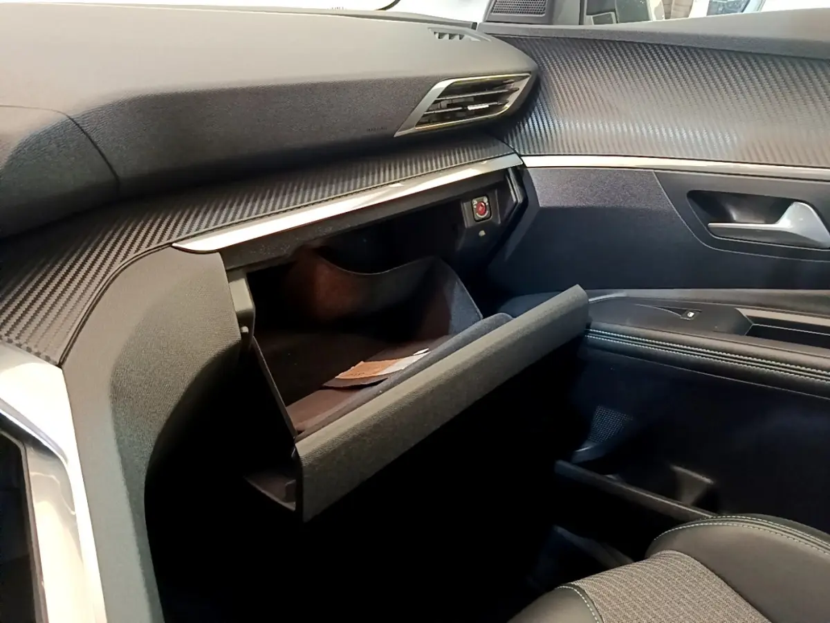 Vue intérieure côté passager du Peugeot 3008 2022 gris foncé, avec boîte à gants ouverte et tableau de bord texturé.