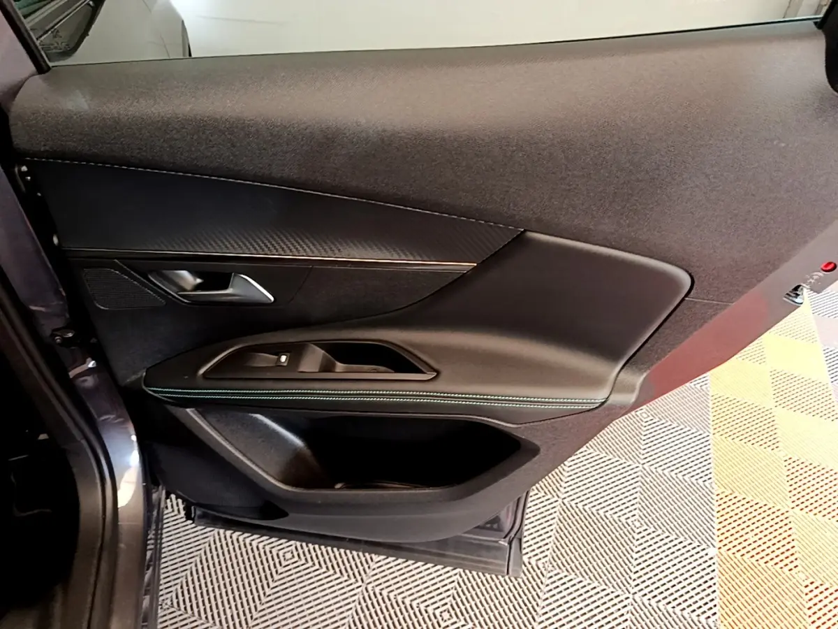 Vue rapprochée de la porte arrière gauche du Peugeot 3008 gris foncé, avec garniture noire et surpiqûres vertes.