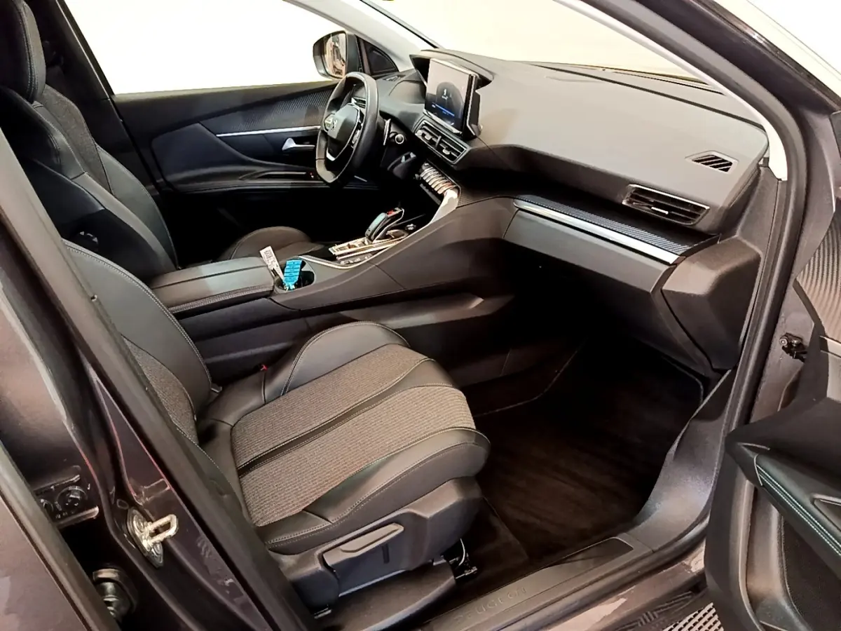 Vue intérieure côté conducteur du Peugeot 3008 gris foncé, avec tableau de bord moderne et écran tactile central.