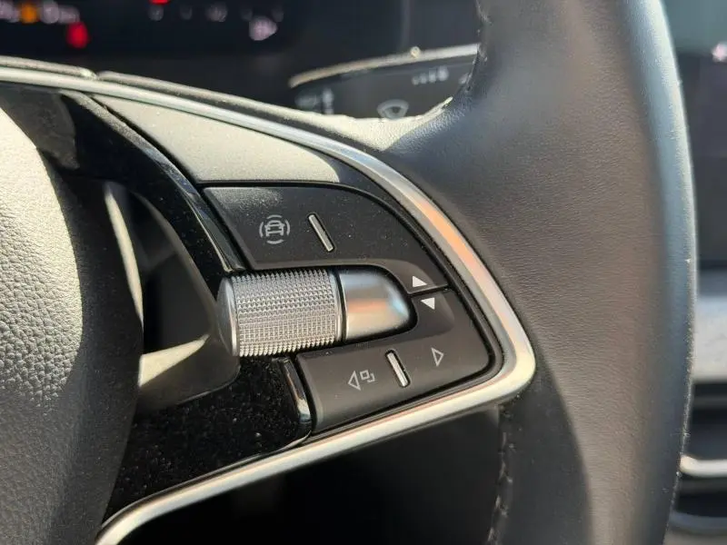 Gros plan sur les commandes au volant du Skoda Kamiq 2025, finition Gris Graphite métallisé, avec molette et boutons noirs.