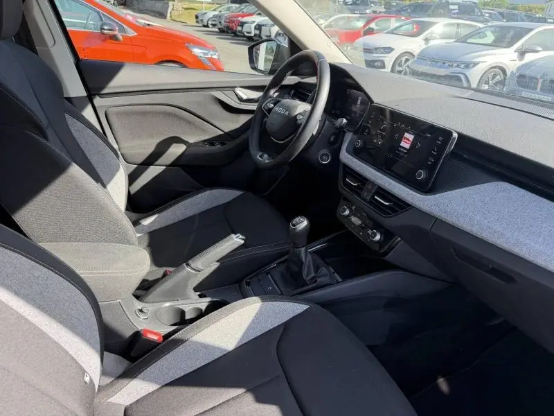 Vue intérieure côté conducteur du Skoda Kamiq 2025, montrant le volant, la console centrale avec boîte manuelle et les sièges bicolores.