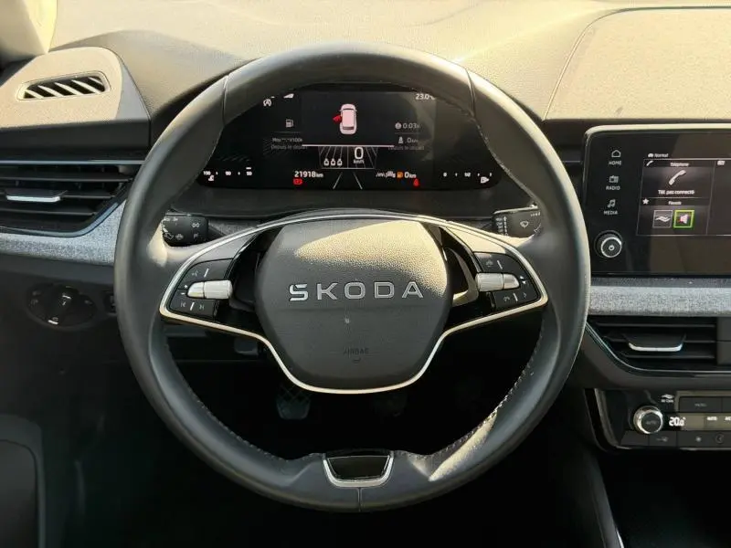 Vue intérieure centrée sur le volant SKODA du KAMIQ 2025 avec tableau de bord numérique et écran tactile à droite.