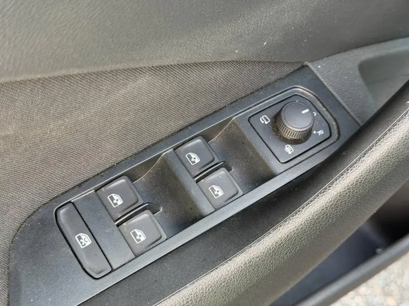 Gros plan sur les commandes des vitres et rétroviseurs côté conducteur du Skoda Kamiq 2025 en Gris Graphite métallisé.