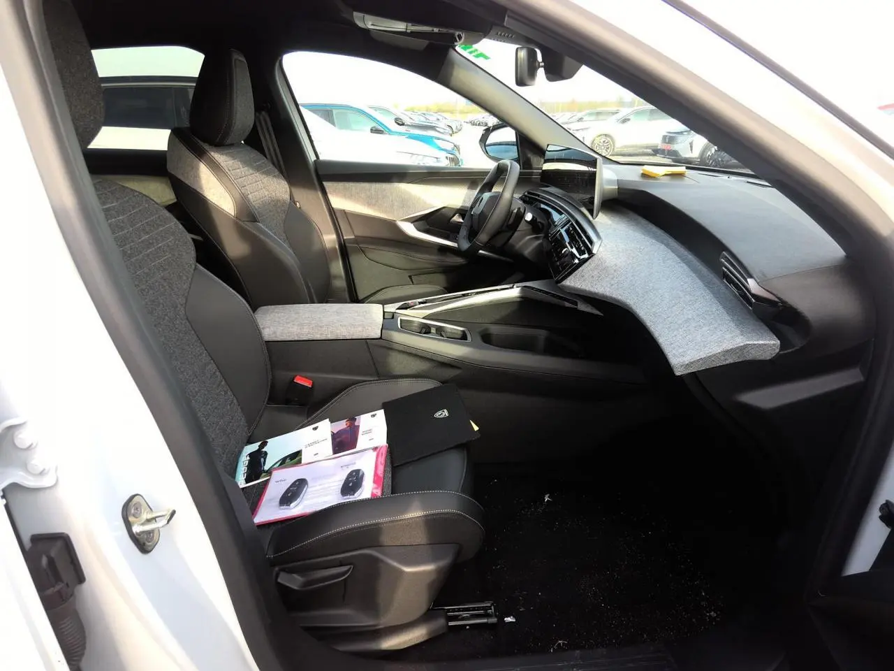 Intérieur avant droit du Peugeot 3008 blanc 2025, avec tableau de bord tissu gris et sièges bi-matière noirs et gris.