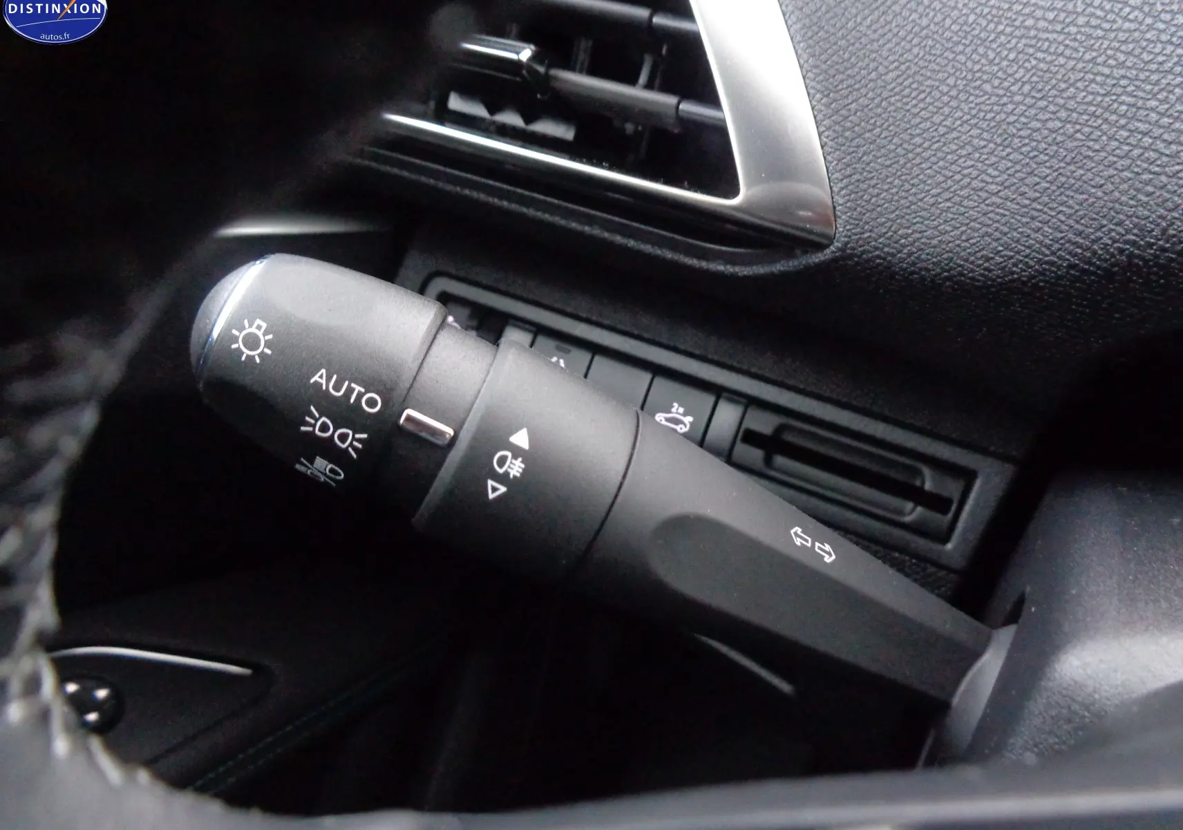 Gros plan sur la commande des feux et clignotants dans l'habitacle noir du Peugeot 3008 gris platinium 2023.