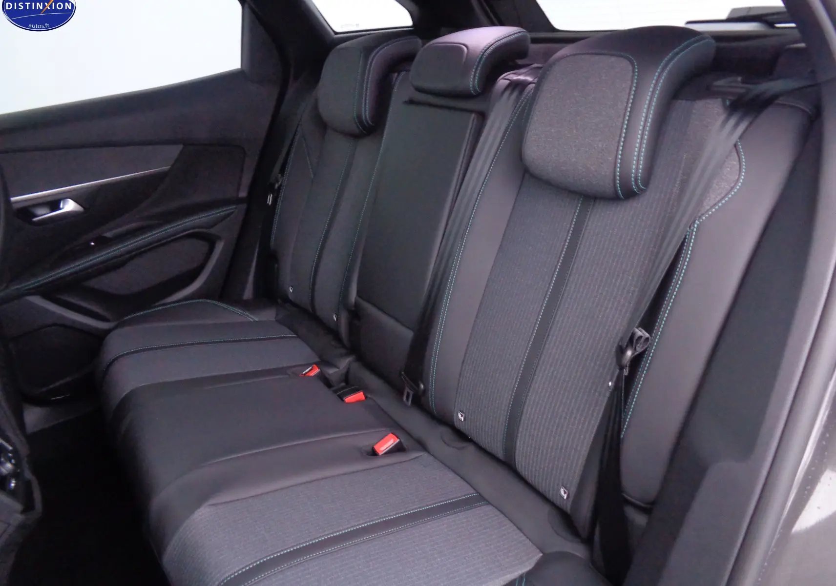 Vue intérieure arrière du Peugeot 3008 2023, sièges noirs avec surpiqûres bleues et ceintures de sécurité visibles.