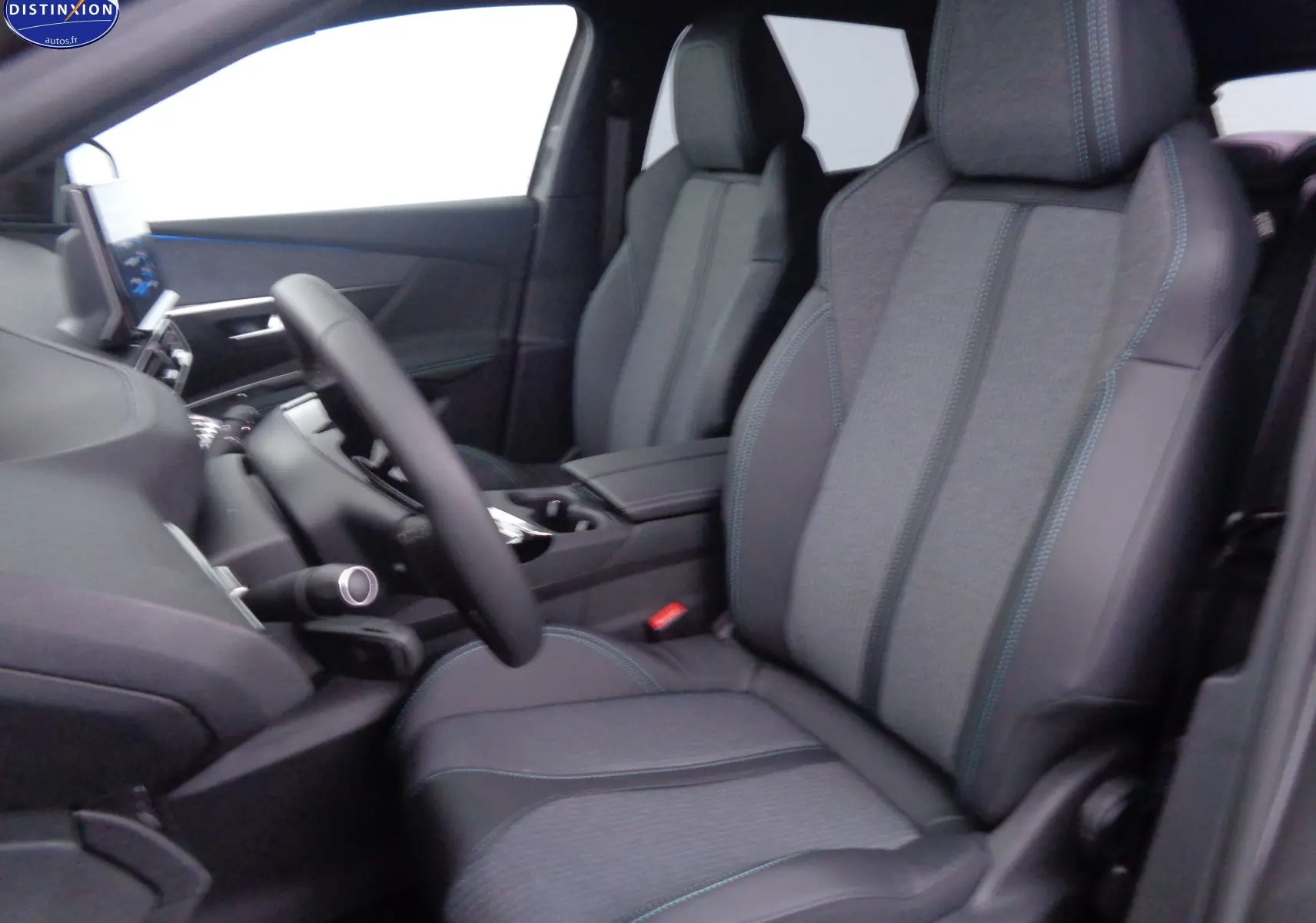 Intérieur du Peugeot 3008 2023, vue côté conducteur, sièges gris tissu et cuir avec surpiqûres bleues, tableau de bord moderne.