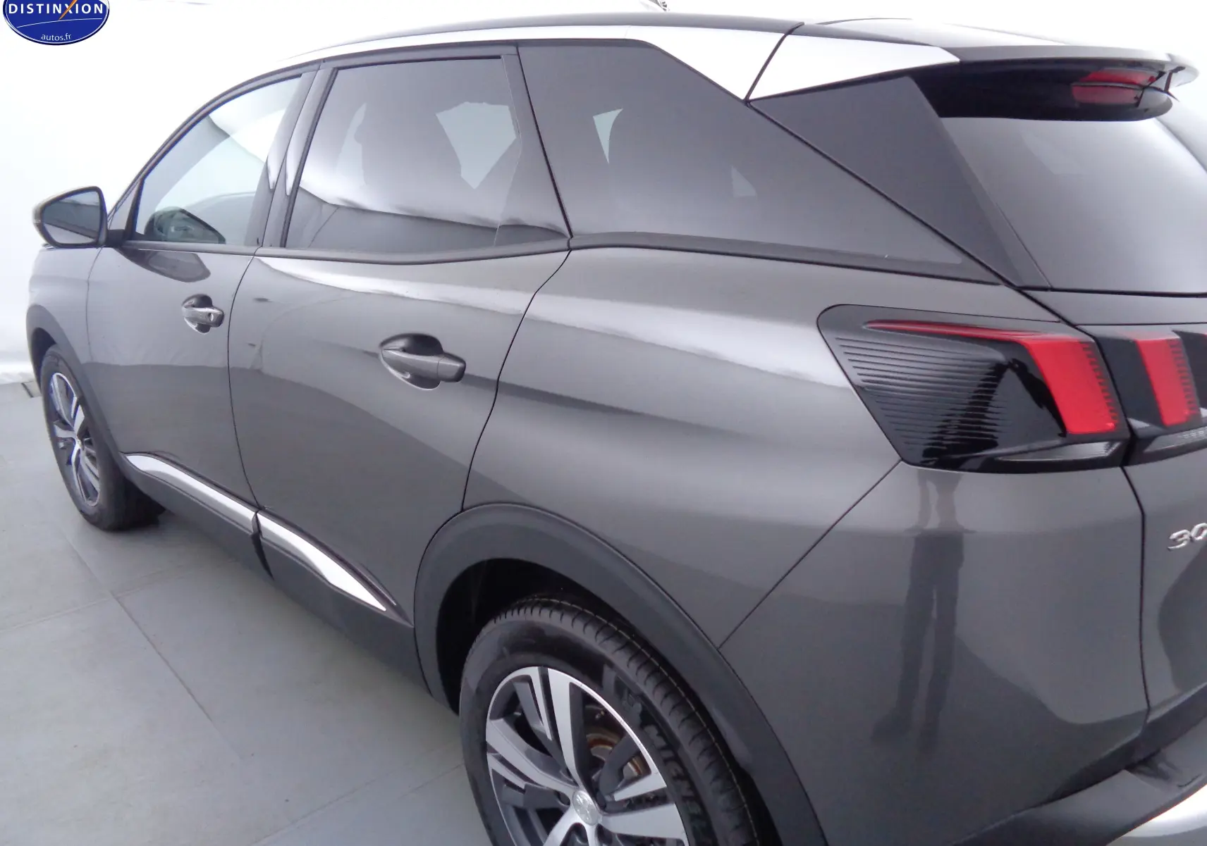 Vue 3/4 arrière gauche d'un Peugeot 3008 gris platinium métallisé avec feux arrière distinctifs et jantes alliage.