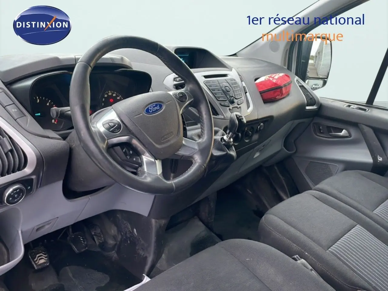 Vue intérieure côté conducteur du Ford Transit Custom blanc de 2016, avec tableau de bord et volant en cuir noir.