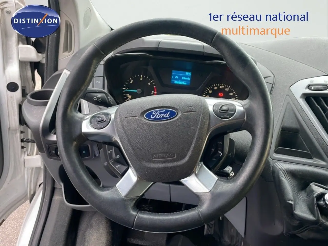 Vue rapprochée du volant Ford noir et tableau de bord du Transit Custom blanc L1H1 2016 avec levier de vitesses manuel.