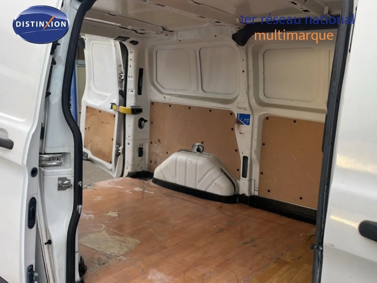 Vue intérieure arrière du fourgon Ford Transit Custom blanc L1H1 2016, montrant l'espace de chargement vide avec plancher en bois.