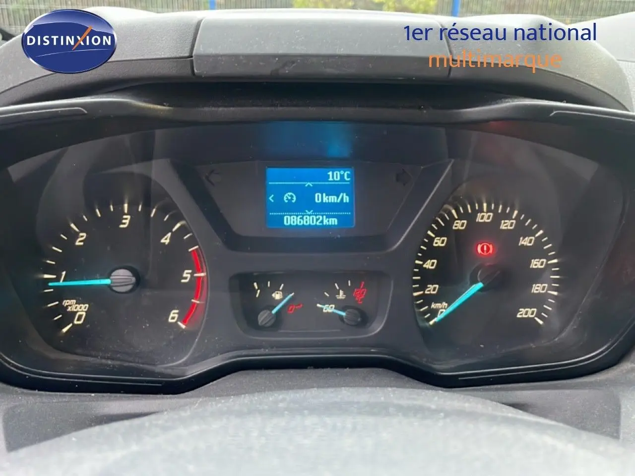 Vue rapprochée du tableau de bord du Ford Transit Custom blanc, affichant 86802 km et vitesse à 0 km/h.