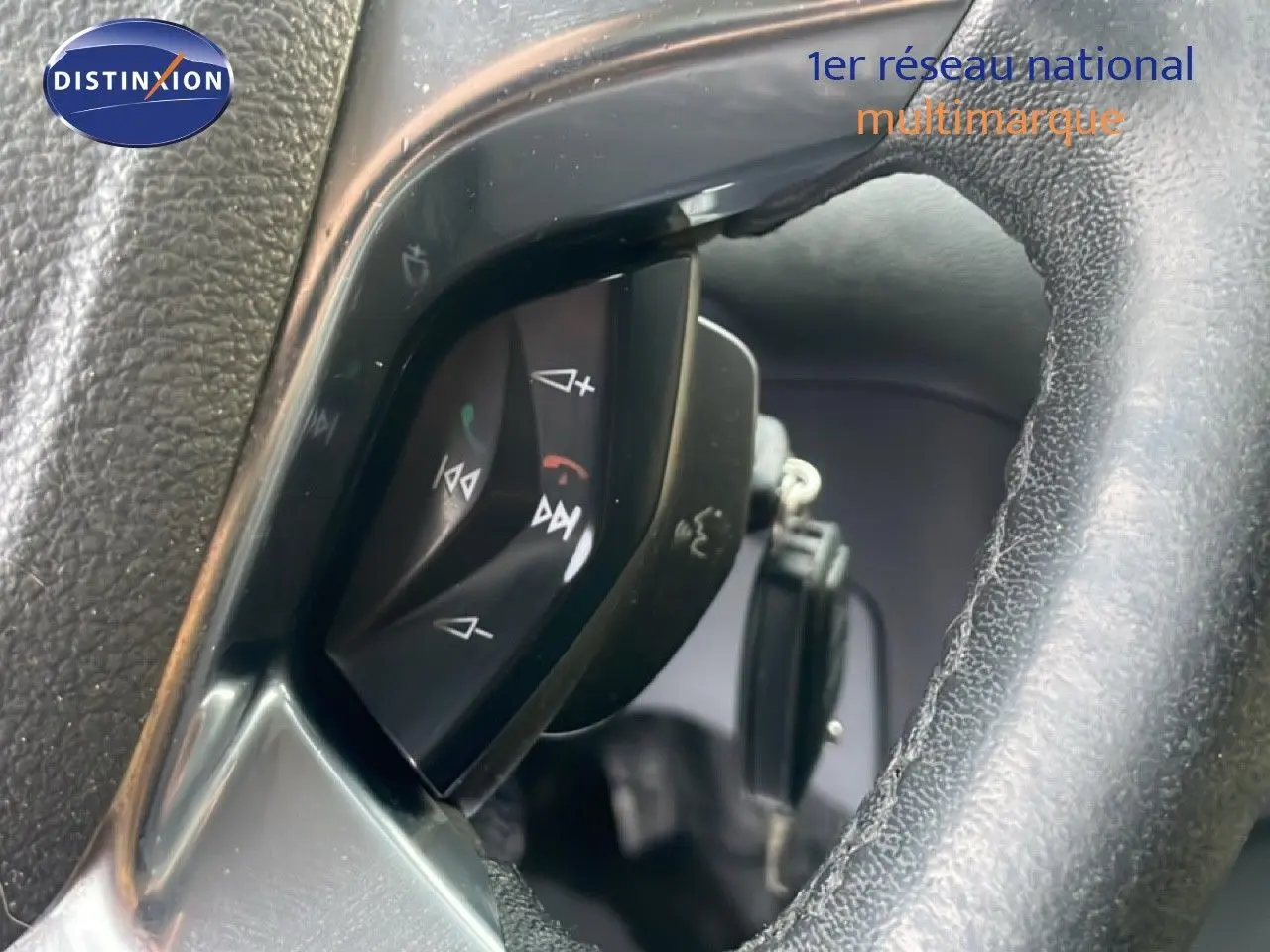 Gros plan sur les commandes au volant d'un Ford Transit Custom blanc, modèle 2016, avec finition noire intérieure.