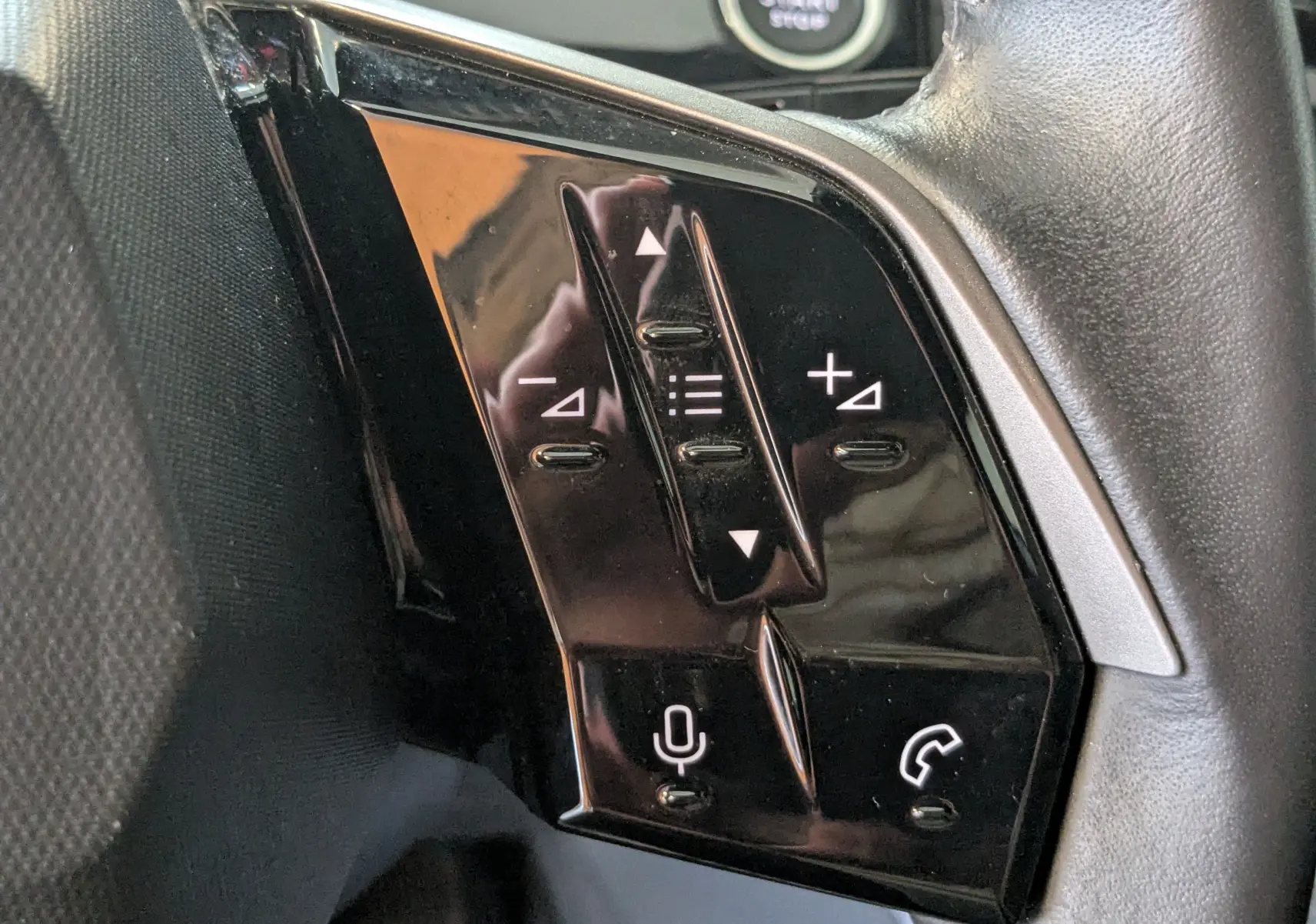 Gros plan sur les commandes noires du volant cuir du Peugeot 3008 Hybrid 145 eDCS6 Allure blanc, avec boutons de volume et téléphone.