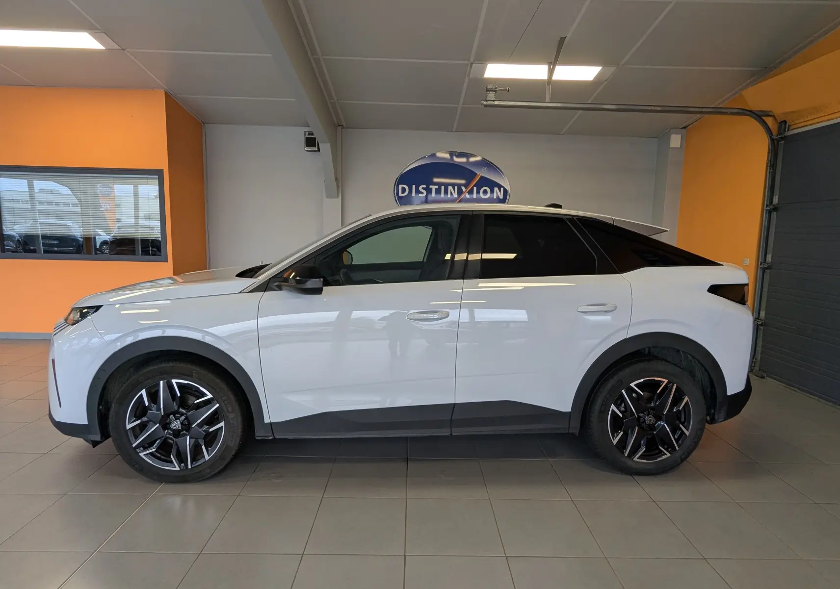 Vue latérale droite du Peugeot 3008 Hybrid blanc avec jantes aluminium 19'' bicolores en showroom.