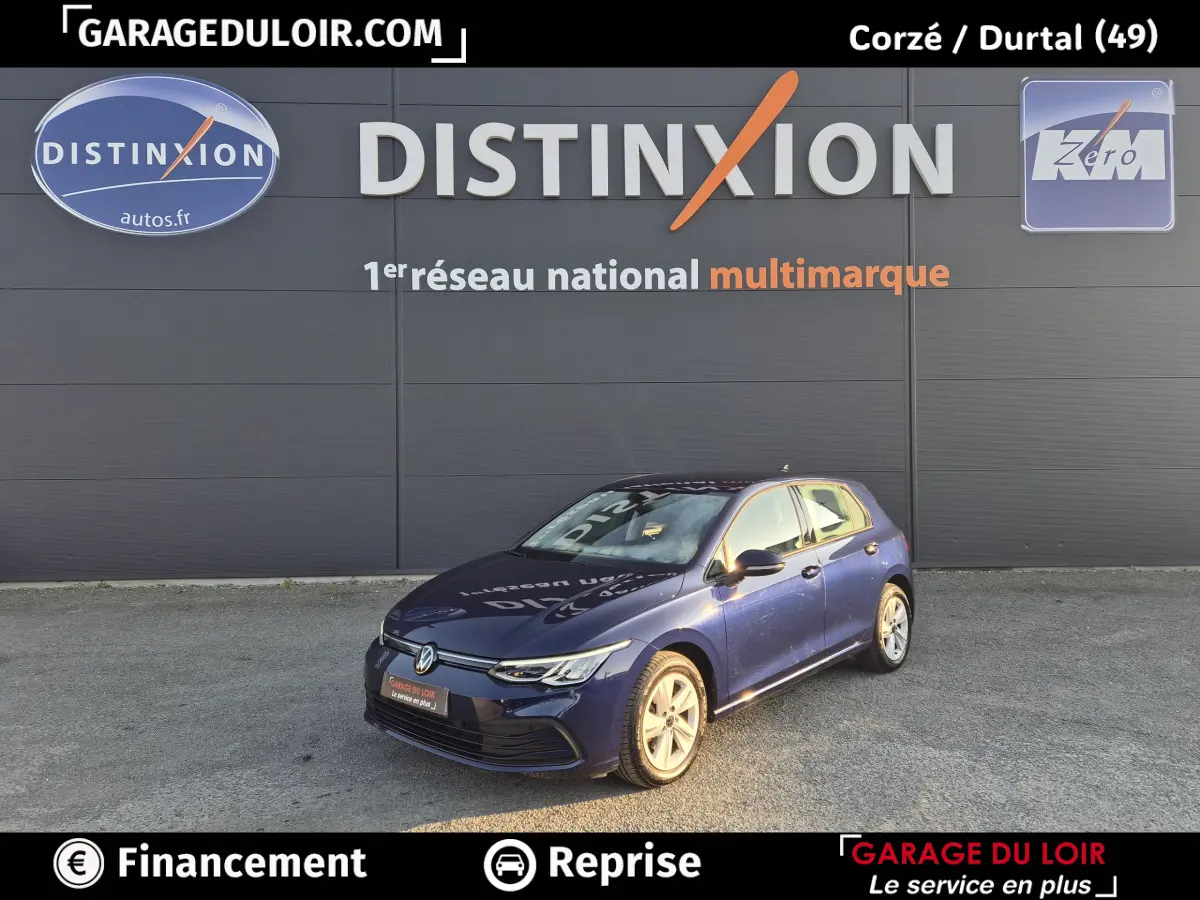 Volkswagen Golf bleu vue 3/4 avant droit, avec phares LED et jantes alliage visibles, stationnée devant un mur gris.