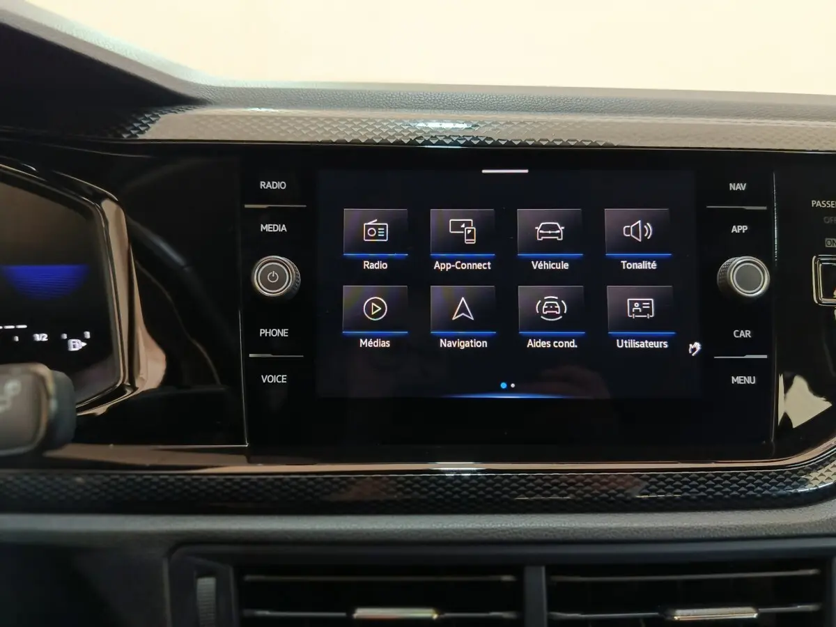 Écran tactile central allumé du Volkswagen Taigo gris foncé, affichant le menu principal multimédia et navigation.
