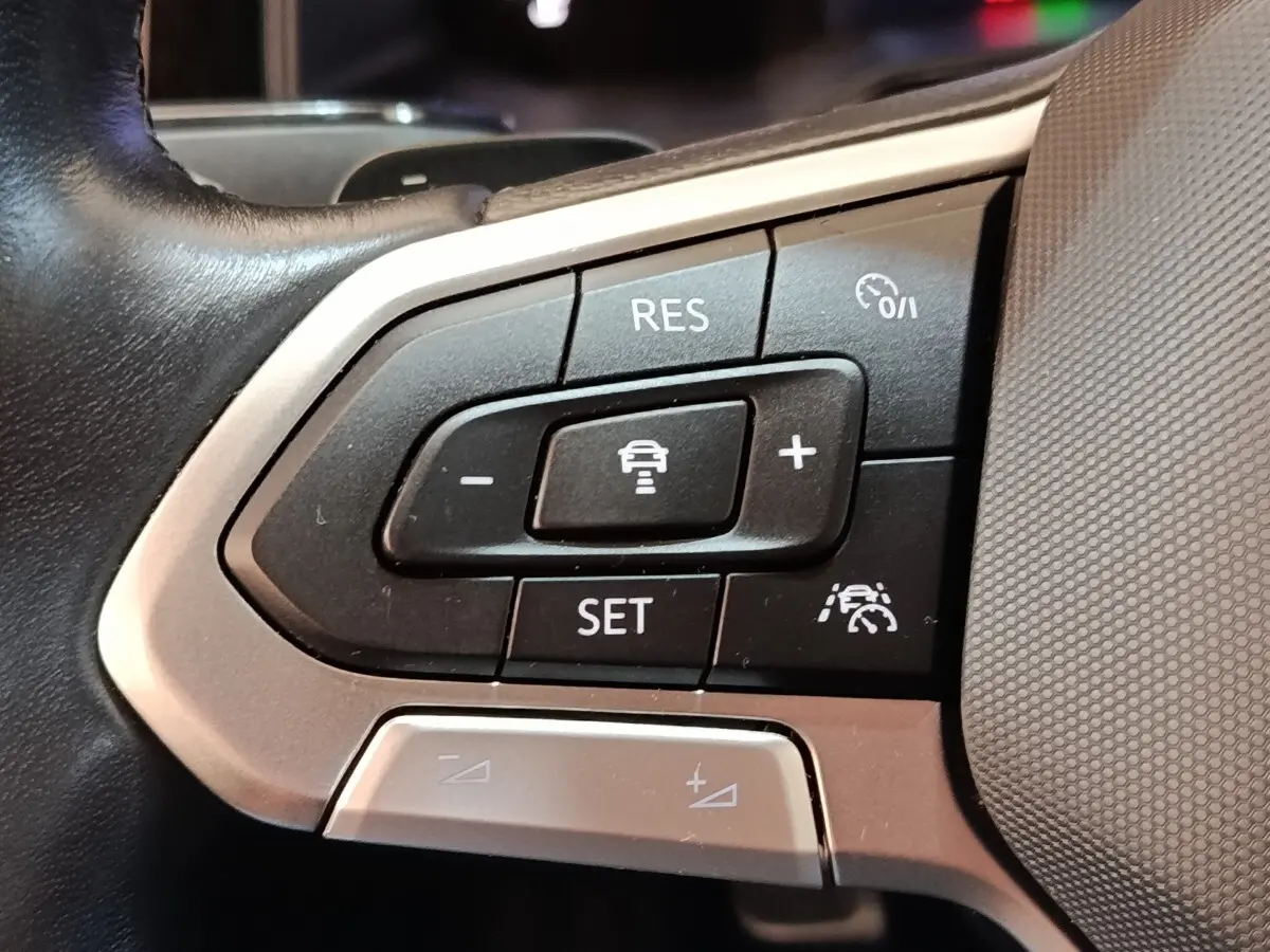 Gros plan sur les commandes du régulateur de vitesse au volant d’un Volkswagen Taigo gris foncé 2023.
